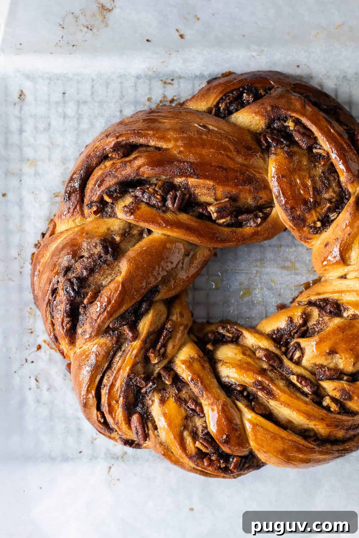 Maple pecan bread wreath – this impressive vegan maple pecan couronne is a real showstopper which would be perfect for an indulgent breakfast or brunch. #veganbaking #eggless #dairyfree #bread #veganbreakfast #veganbrunch Close up of an unglazed loaf of maple pecan couronne.
