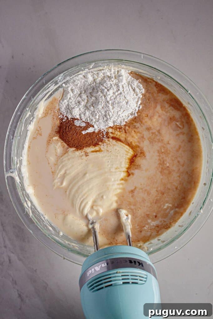 Decadent RumChata Cheesecake Recipe: Creamy Liqueur Dessert 7 Cinnamon and cornstarch being mixed into batter.