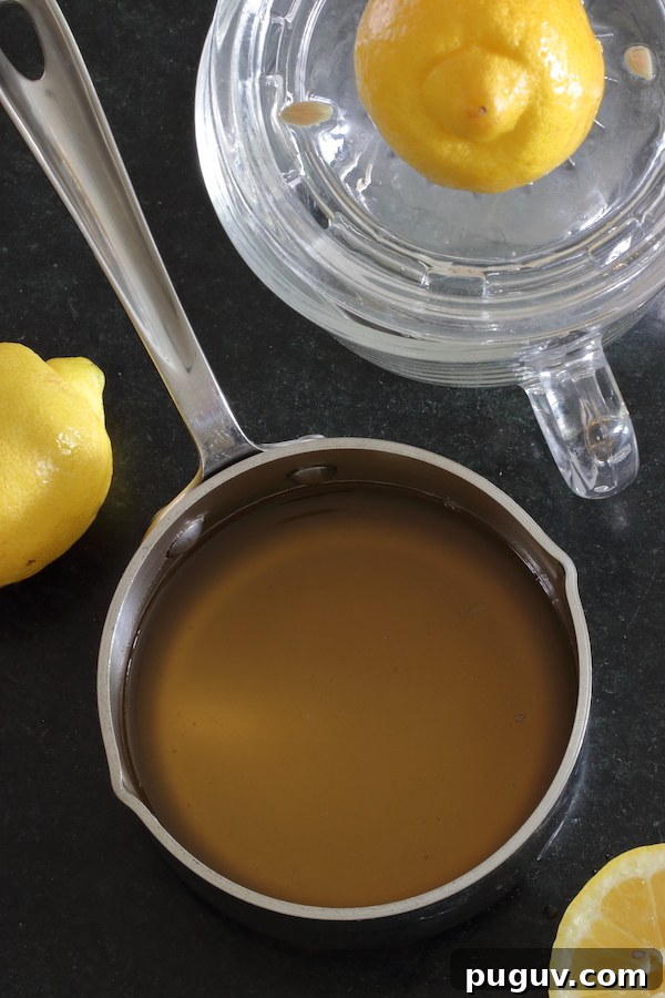 A small saucepan of simple syrup surrounded by lemons