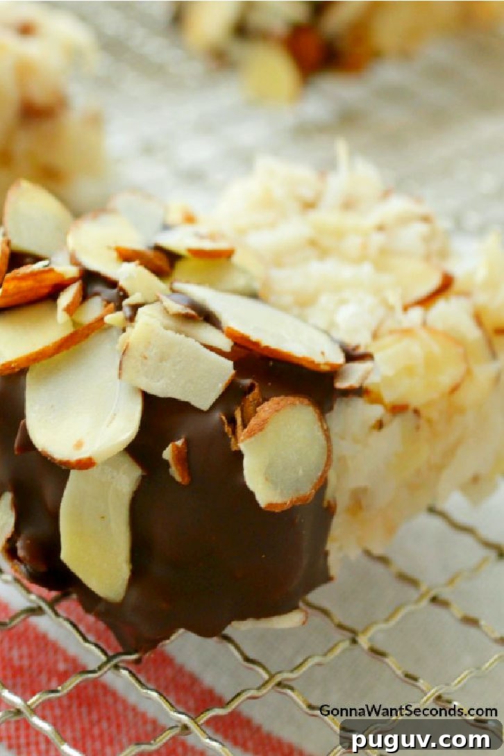 These Coconut Almond Macaroons are sheer perfection! Ooey Gooey and moist, loaded with coconut, dipped in chocolate, and sprinkled with sliced almonds. Chocolate Dipped Coconut Almond Macaroons on a cooling rack