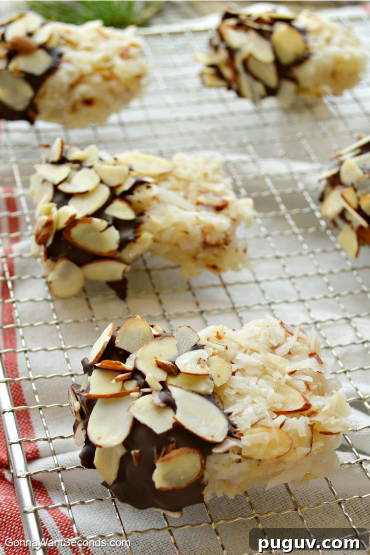These Coconut Almond Macaroons are sheer perfection! Ooey Gooey and moist, loaded with coconut, dipped in chocolate, and sprinkled with sliced almonds. Chocolate Dipped Coconut Almond Macaroons on a cooling rack