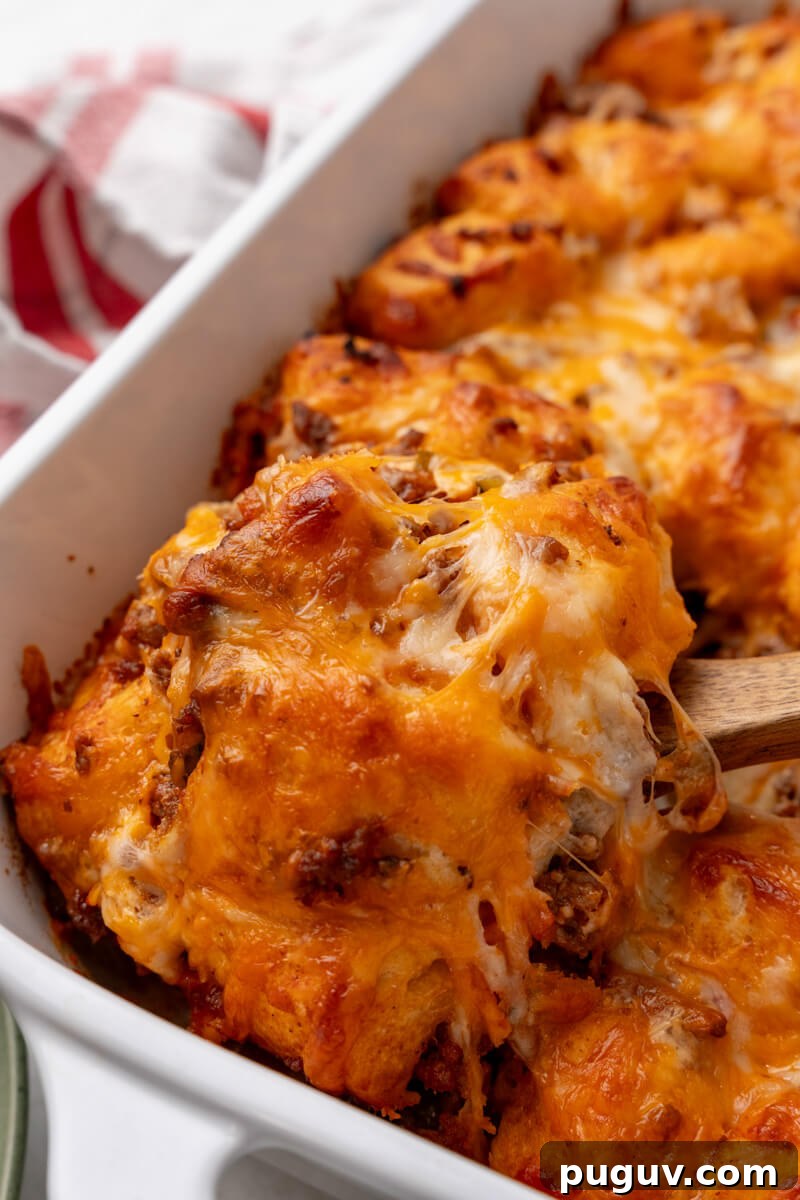 A wooden spoon takes a scoop out of the casserole.