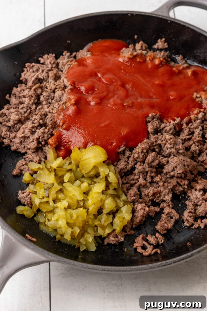 The sauce and pickles are added to the ground beef.