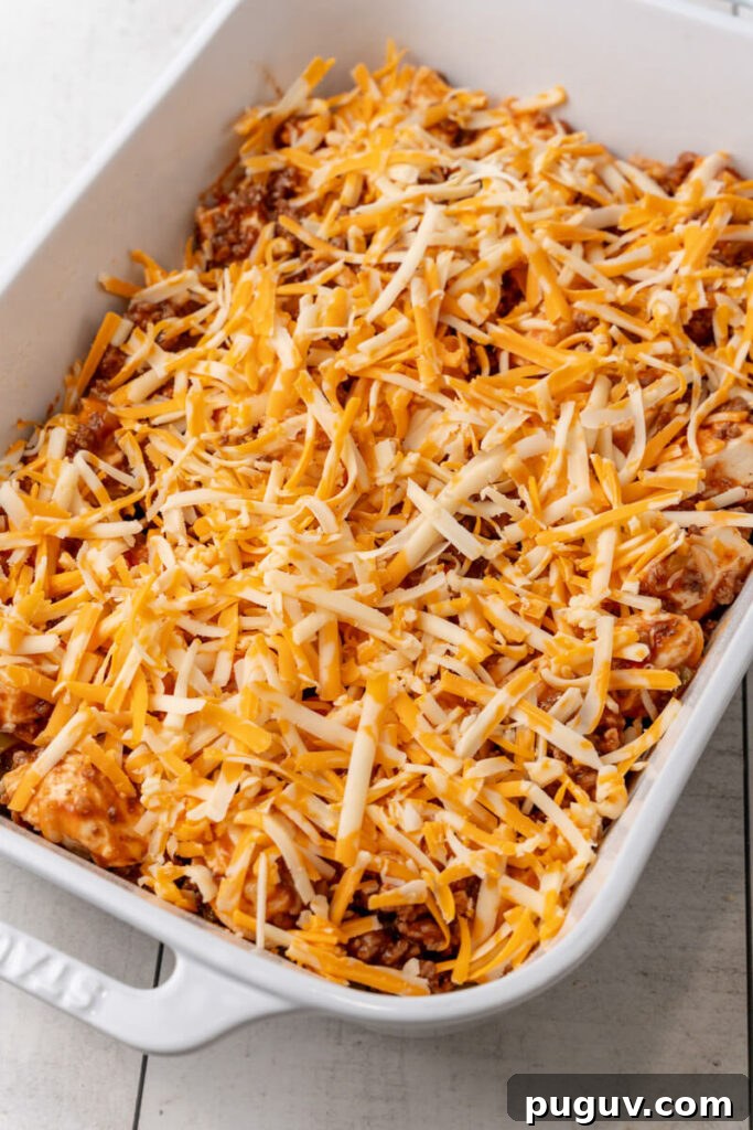 The mixture is added to the casserole dish and topped with shredded cheese.