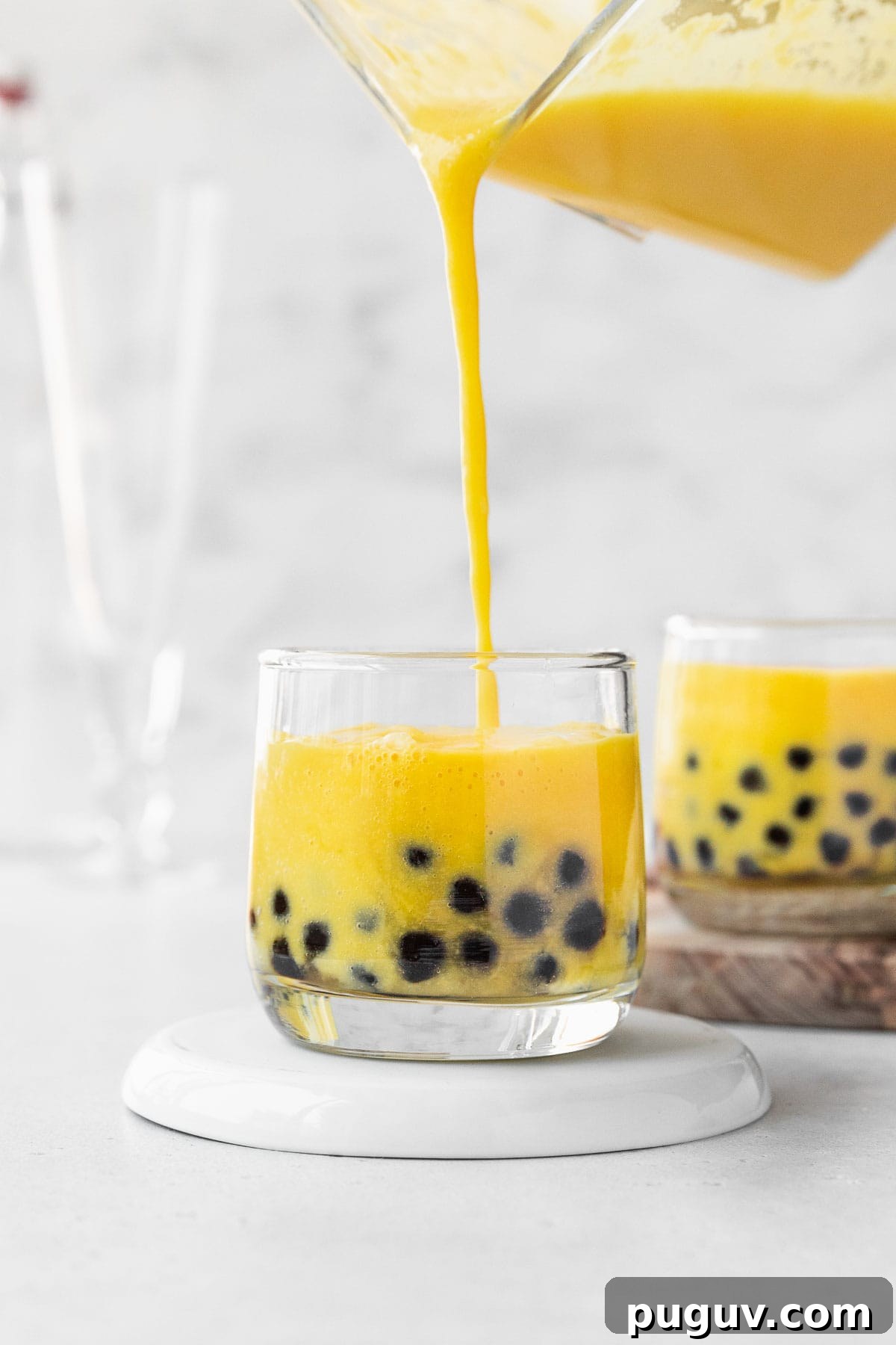 Filling up a small glass with mango boba tea.