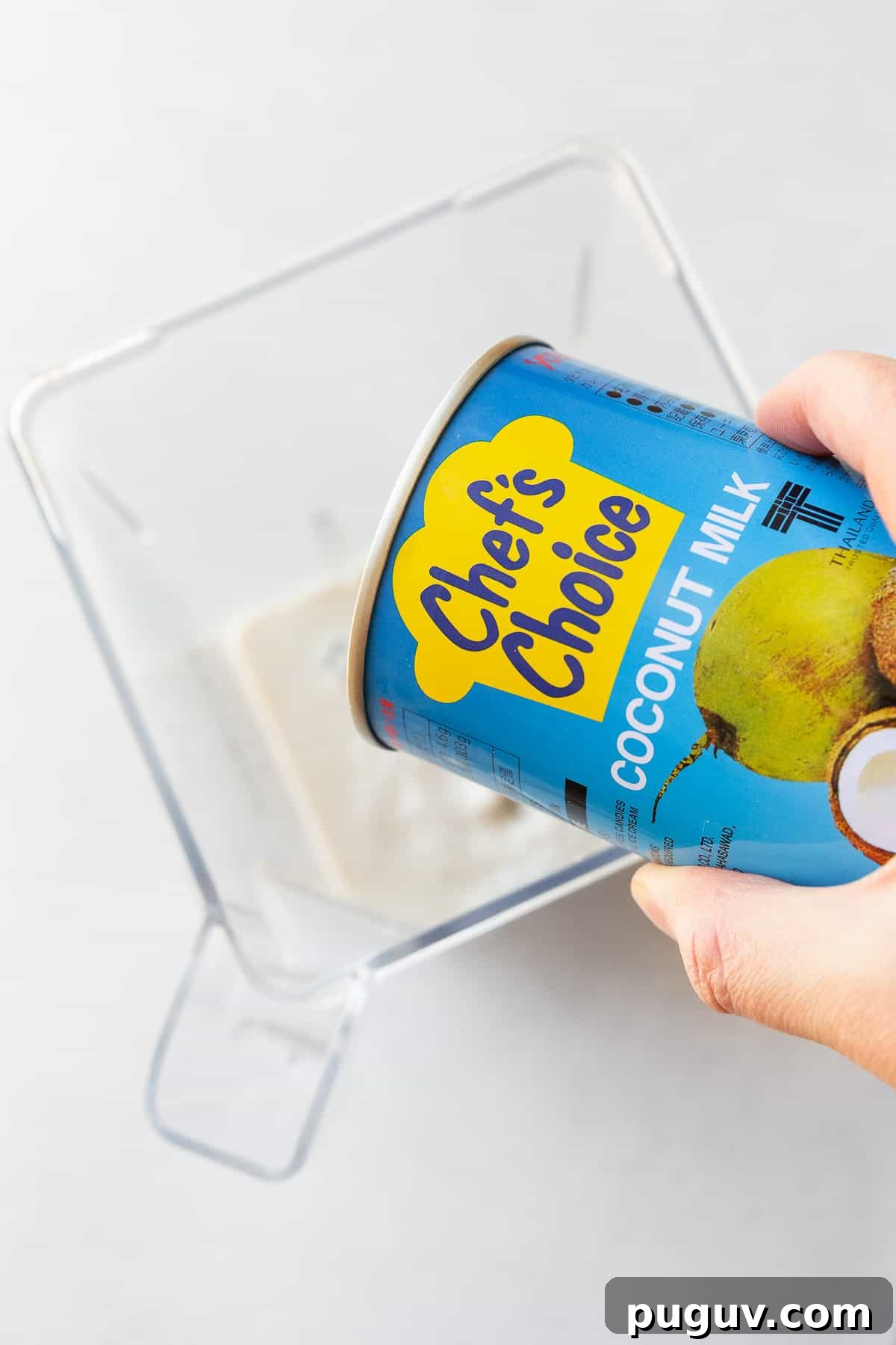 Adding coconut milk to a blender.