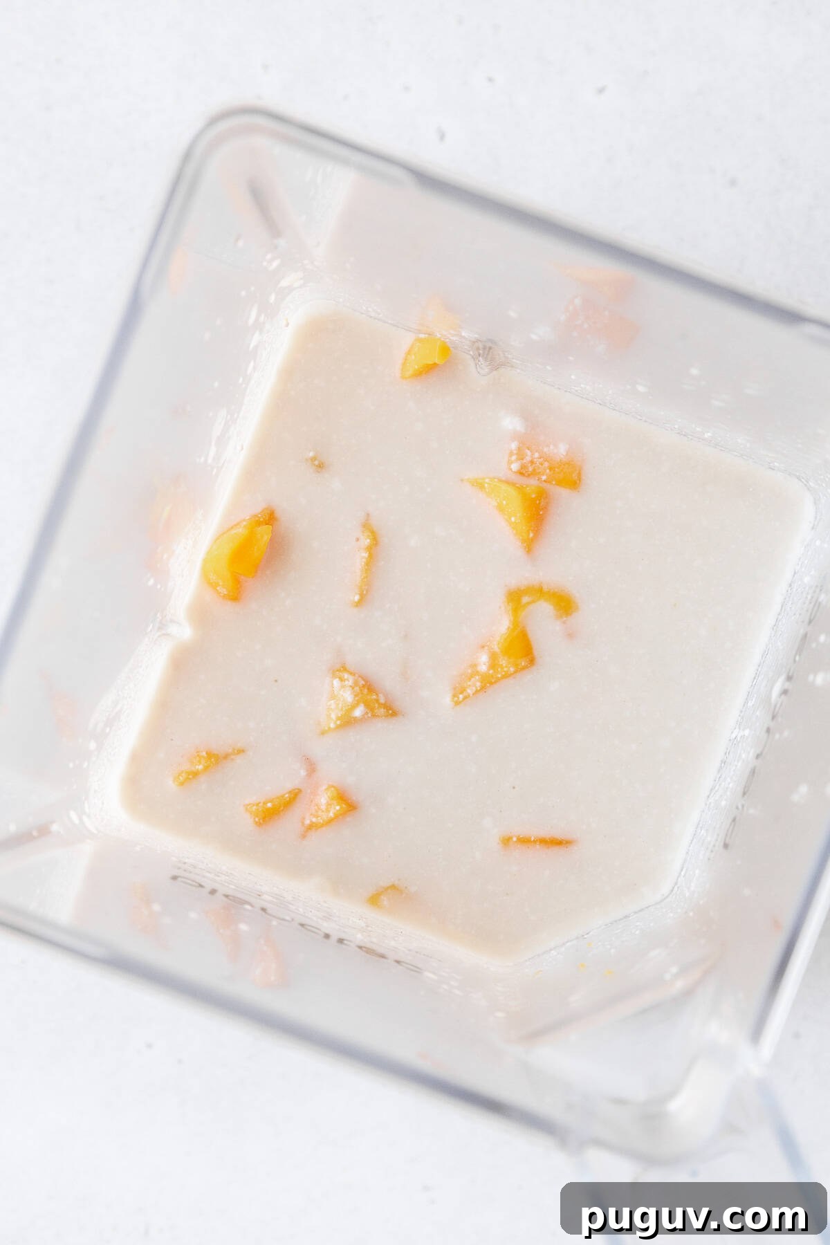 Cubed mango, tea, and coconut milk in a blender.