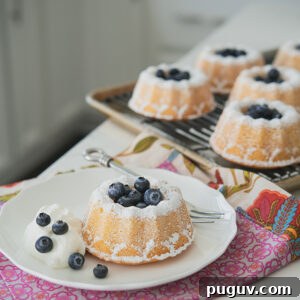 Warm Hot-Milk Mini Bundt Cakes with Vanilla Glaze 4 Hot milk mini bundt cakes are garnished with fresh blueberries and cream.