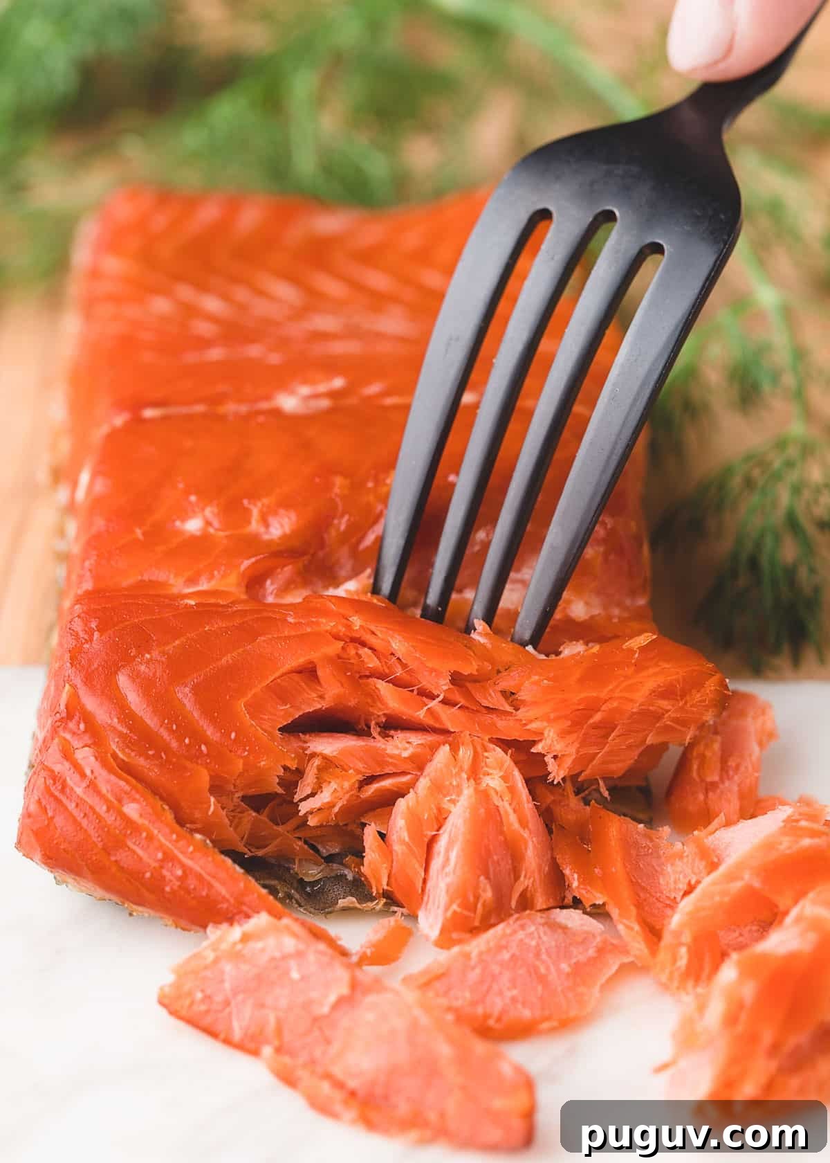 Smoked Salmon, Leek & Goat Cheese Frittata Recipe 3 fillet of hot smoked salmon on a wood and marble board being flaked with a fork