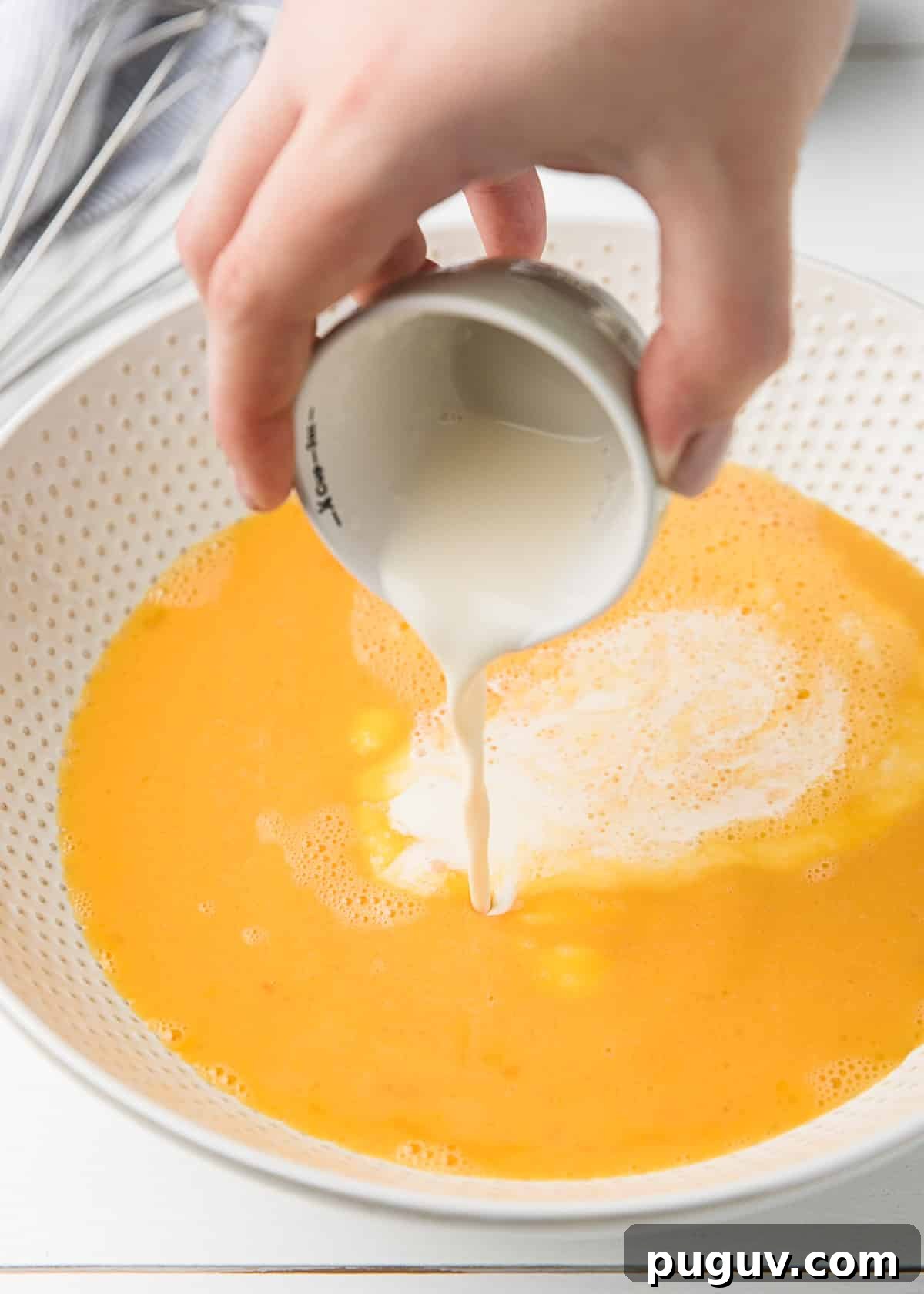 Smoked Salmon, Leek & Goat Cheese Frittata Recipe 6 pouring heavy cream into a white ceramic bowl of beaten eggs