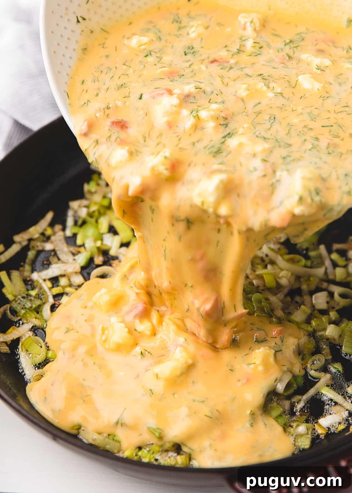 Smoked Salmon, Leek & Goat Cheese Frittata Recipe 7 frittata egg mixture being poured over sauteed leeks in a frying pan