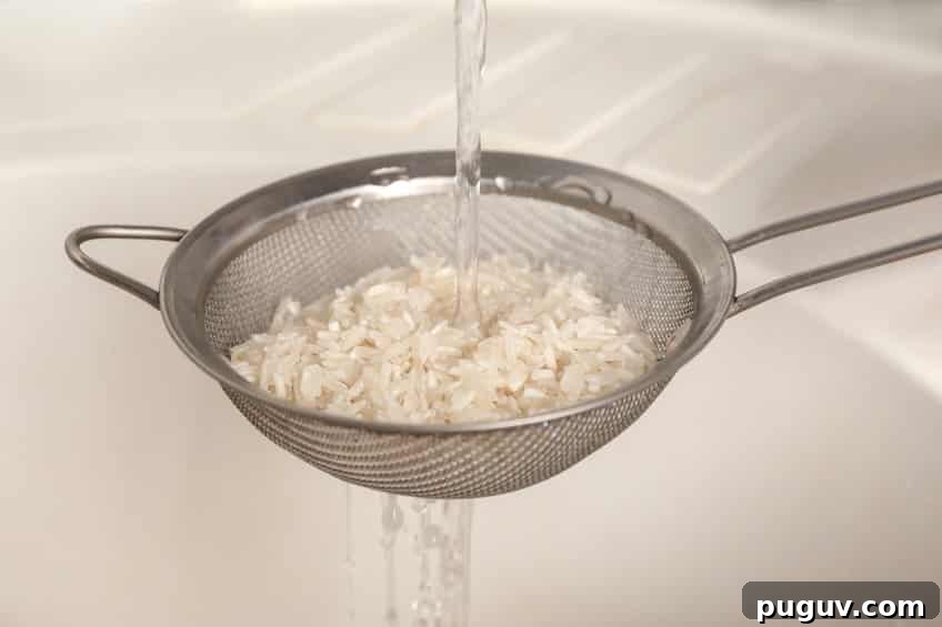 rinsing rice in a strainer with cool water running over it