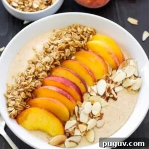 Creamy Peach Smoothie Bowl Recipe for Summer Breakfast 5 Peach pie smoothie in a white bowl topped with freshly sliced peaches, granola and sliced almonds.