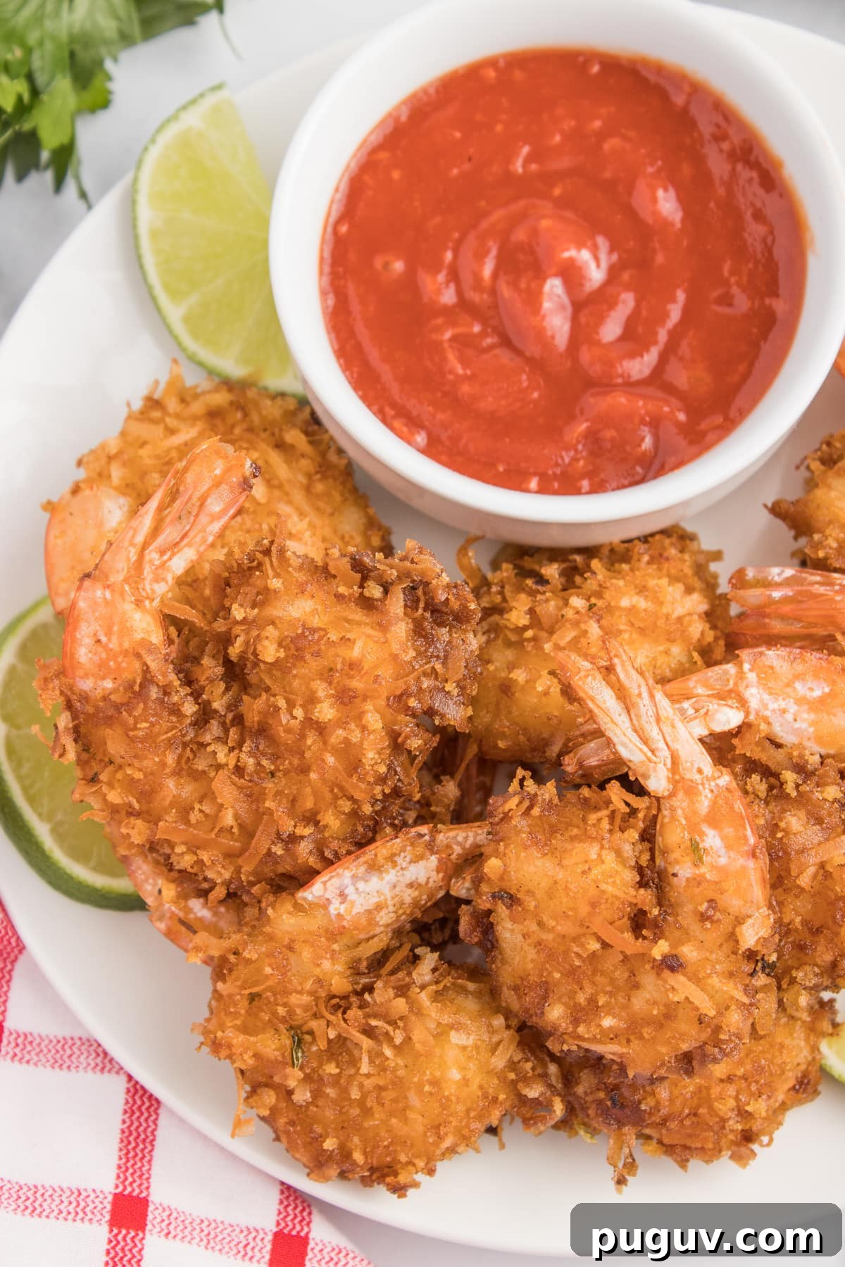Coconut shrimp on a plate with lime slices and sauce