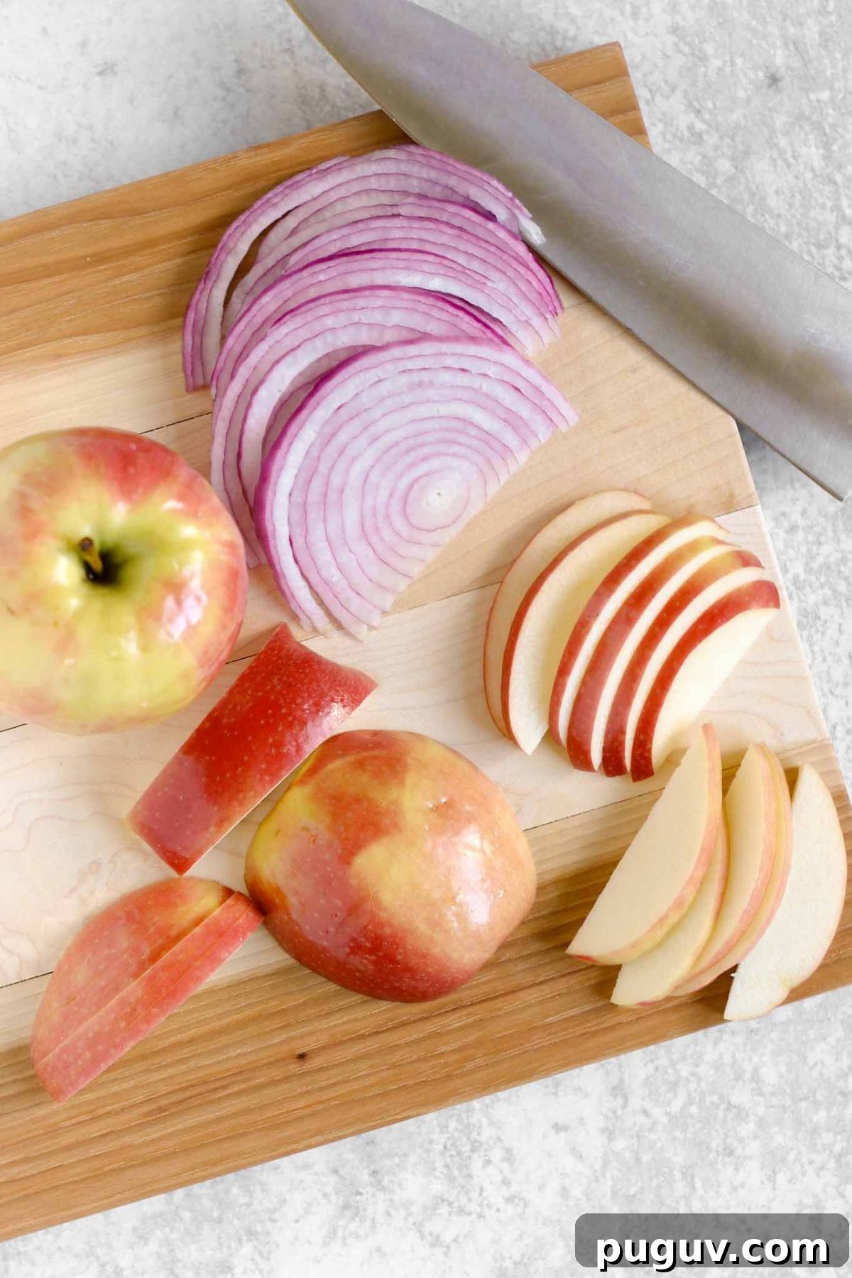 Crisp Apple and Arugula Salad with Toasted Pecans 5 Sliced red onion and apples on a wood cutting board.