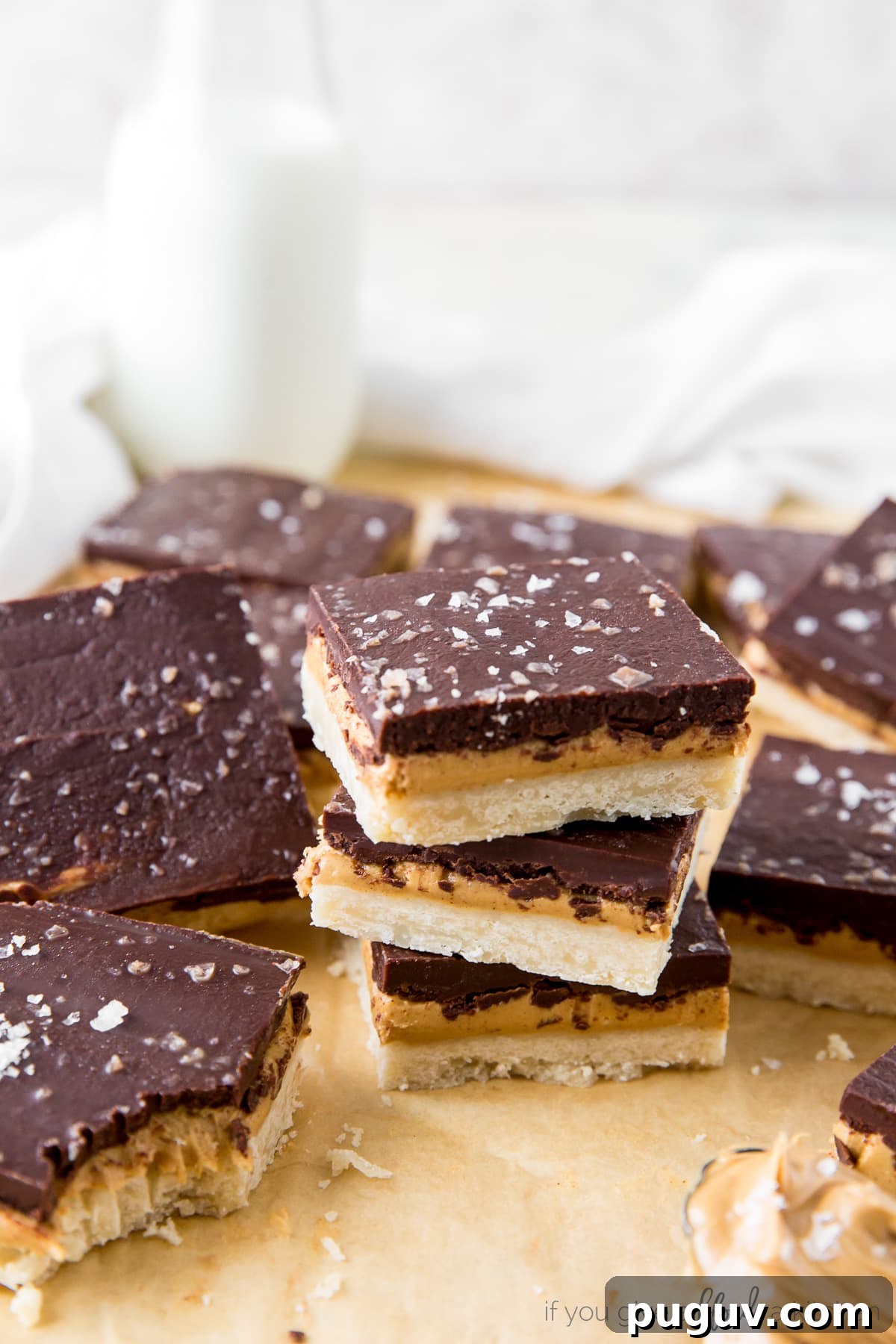 Chocolate Peanut Butter Bars with Shortbread Crust 5 stack of three peanut butter chocolate bars surrounded by more bars on parchment paper