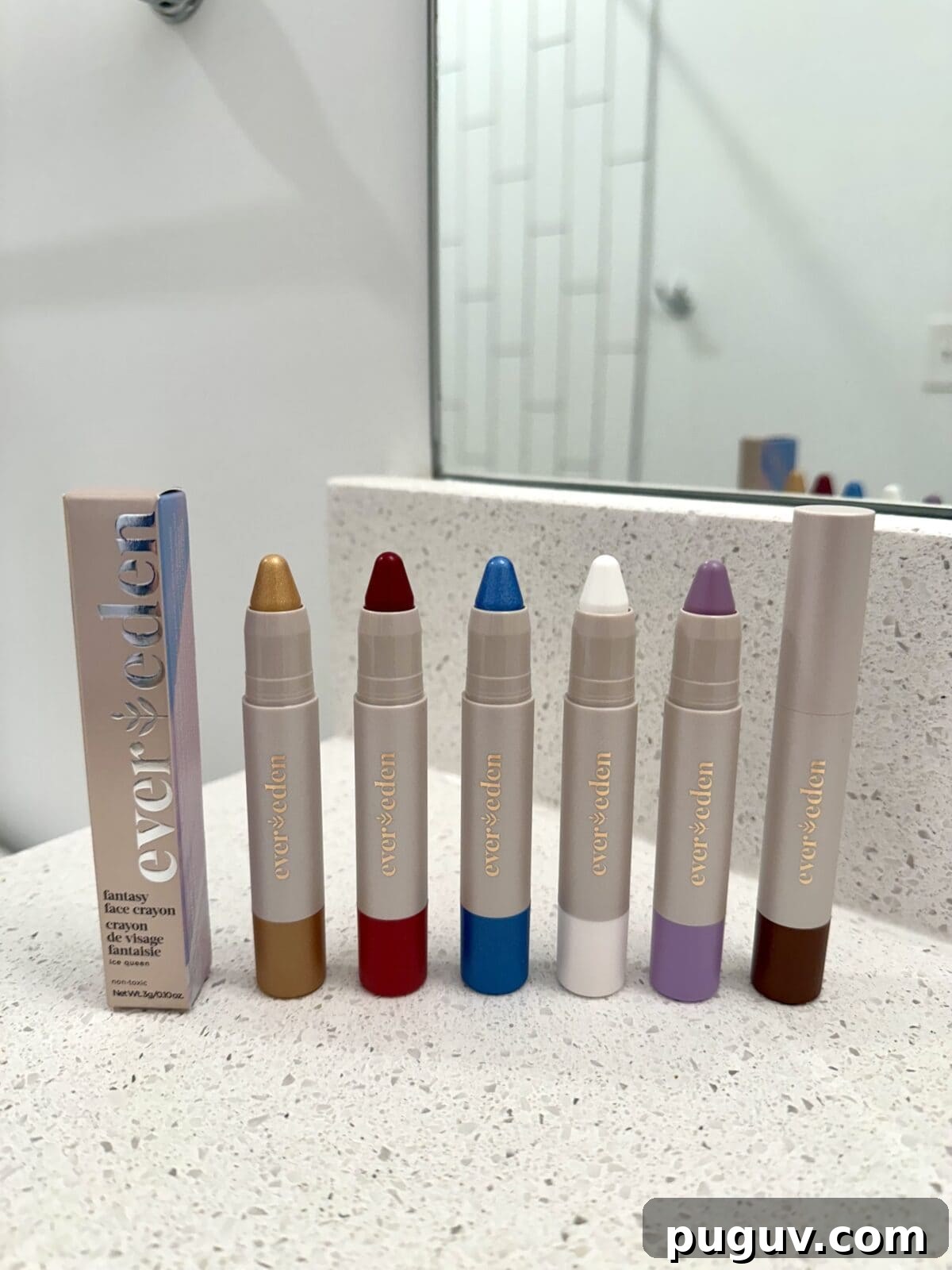 Clean Makeup for Tweens: 8 Safe Brands for Kids and Teens 8 Six colorful Ever Eden face crayons, including gold, red, blue, white, purple, and brown, are displayed upright next to their packaging on a bathroom counter.