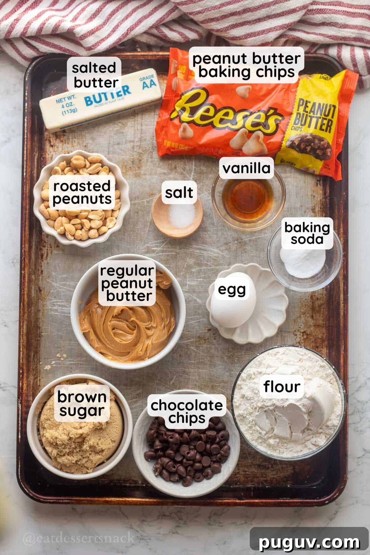 Labeled ingredients of peanut butter cookies on metal baking sheet.