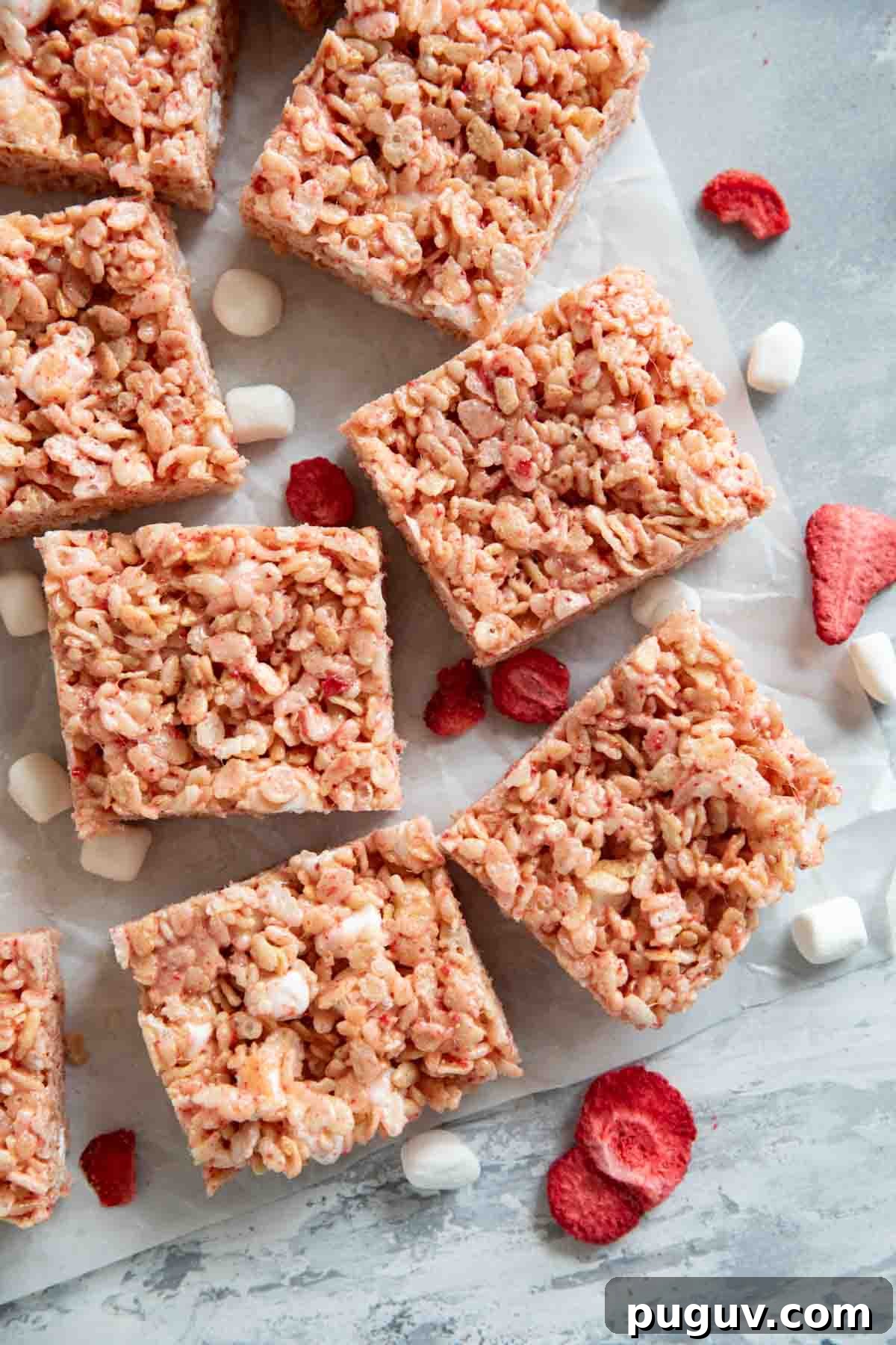 Strawberry Rice Krispie Treats Recipe — Quick No-Bake Dessert 2 Strawberry Rice Krispie Treats cut into bars, with freeze dried strawberries and mini marshmallows.