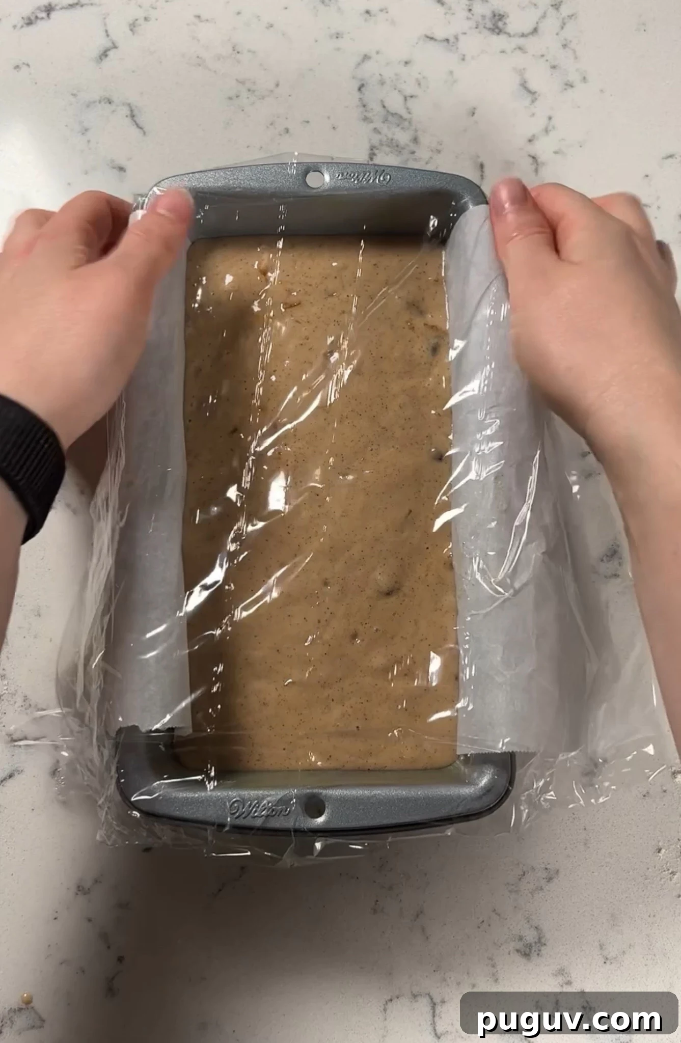 Covering the loaf in plastic wrap.