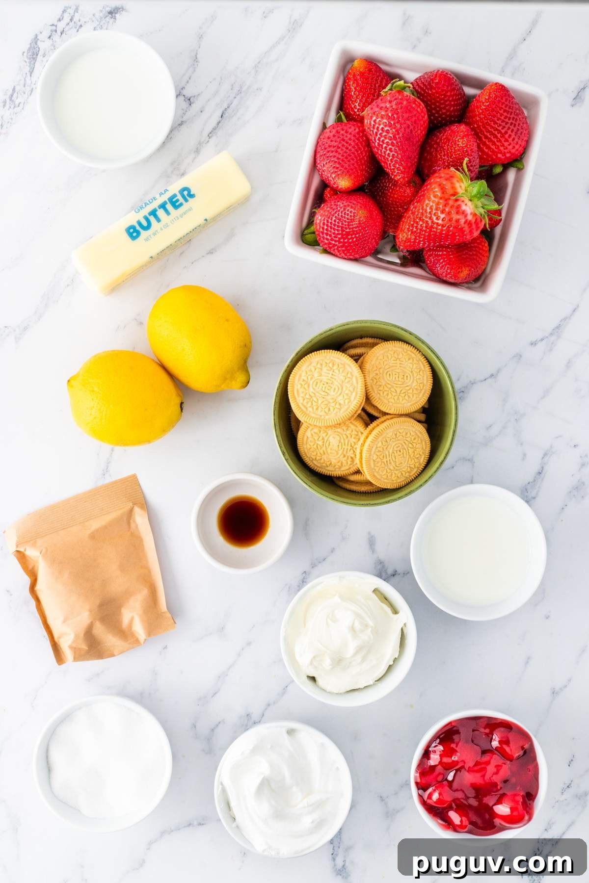 Ingredients laid out on a marble surface include strawberries, lemons, butter, cookies, cream cheese, vanilla extract, sugar, whipped cream, and a bowl of strawberry mixture—perfect for crafting a delectable strawberry lemon cheesecake lasagna.