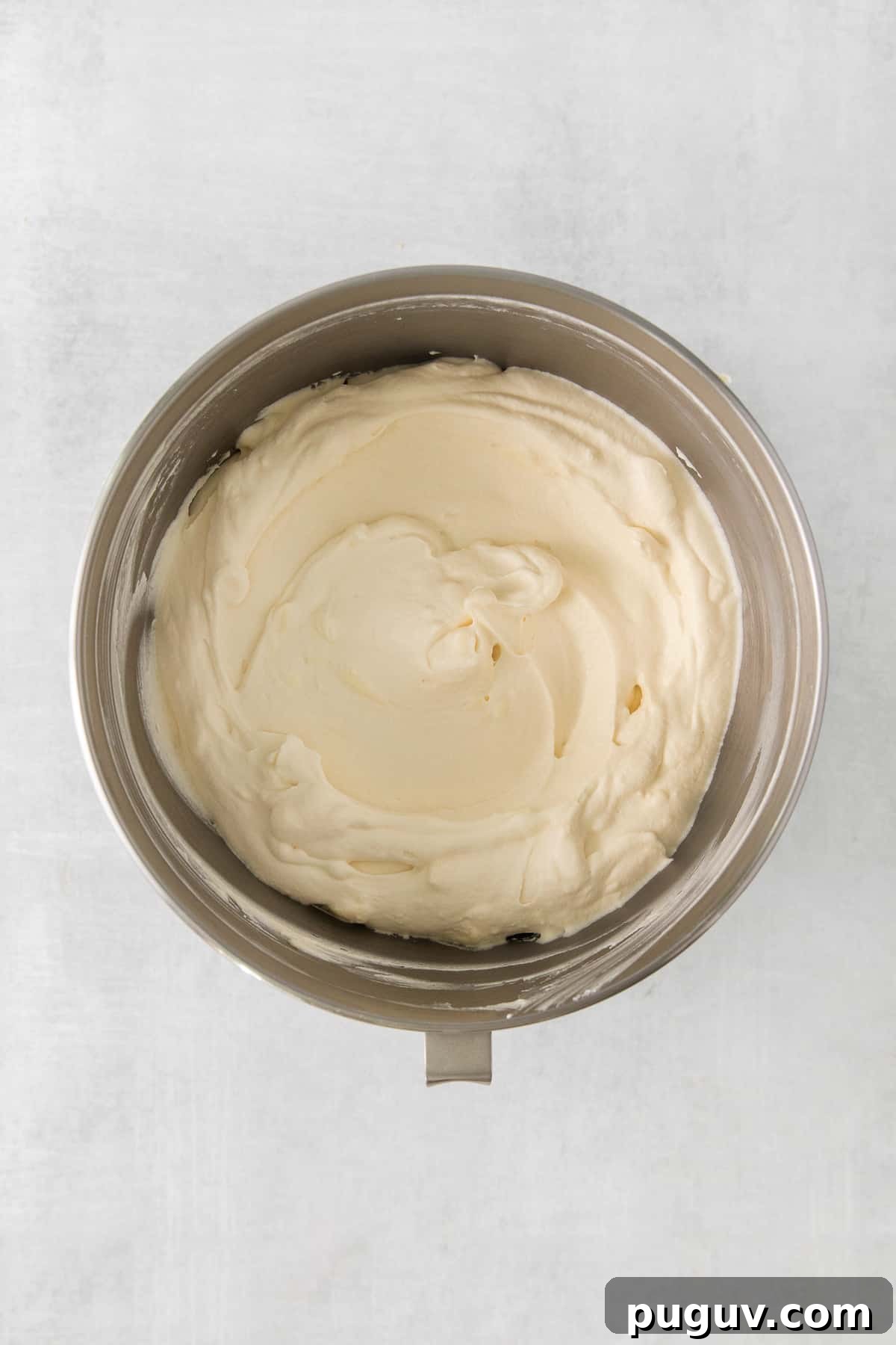 whipped cream in a bowl on a white surface.