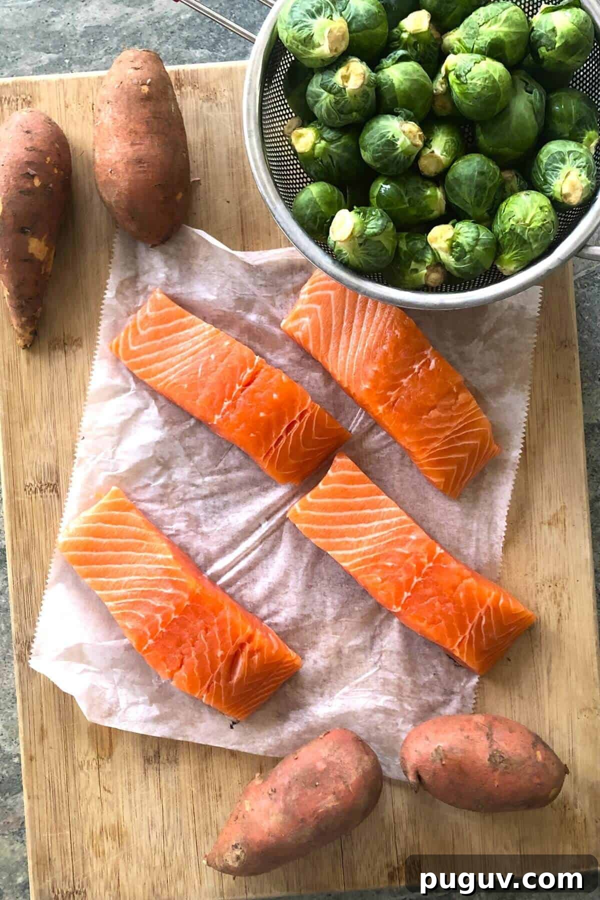 salmon, Brussels sprouts, and sweet potatoes on a cutting board.