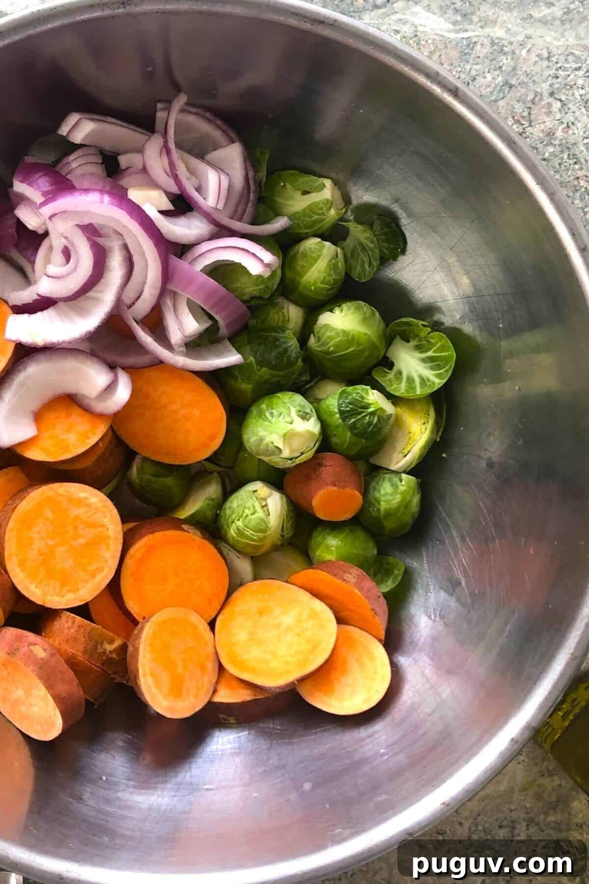 sweet potatoes, Brussels sprouts, red onion in a metal bowl.