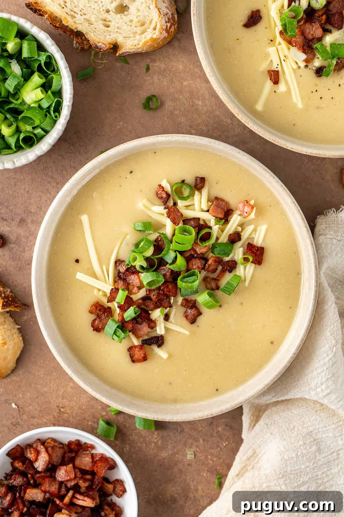 Creamy Dairy-Free Baked Potato Soup Recipe 2 The dairy free baked potato soup served into bowls with crispy bacon, cheese and spring onions.