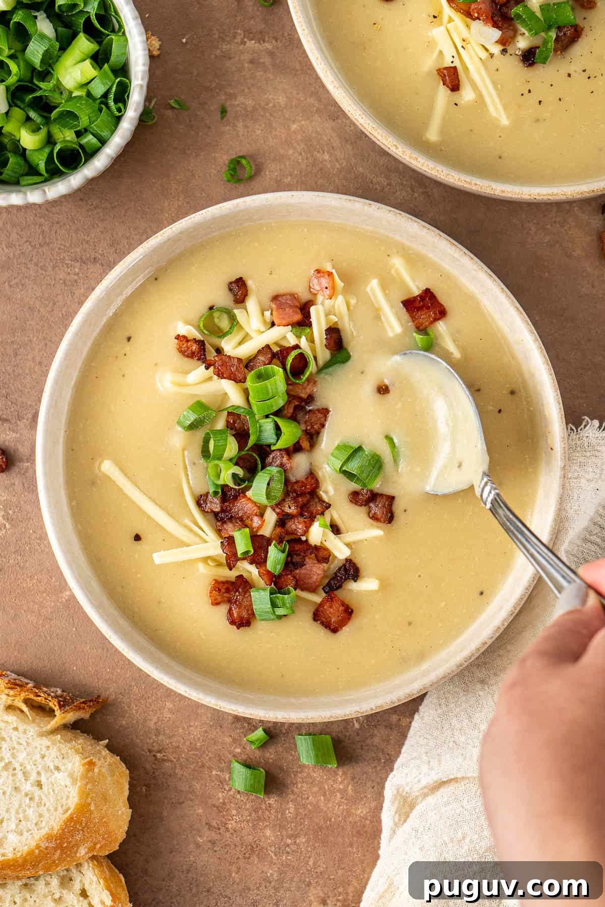 Creamy Dairy-Free Baked Potato Soup Recipe 11 A hand taking a spoonful of baked potato soup.