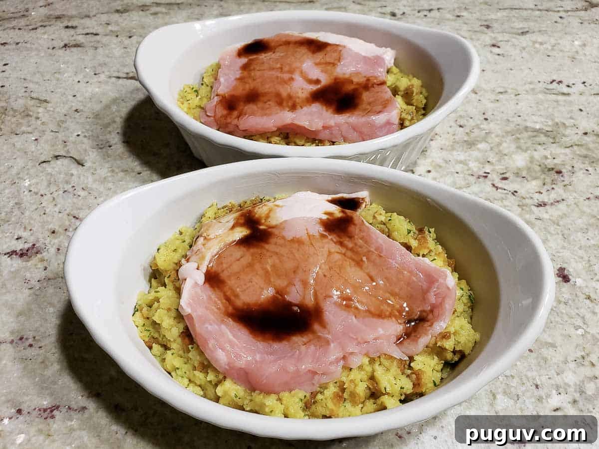 two casserole baking dishes filled with stuffing, pork chops, and topped with Worcestershire sauce.