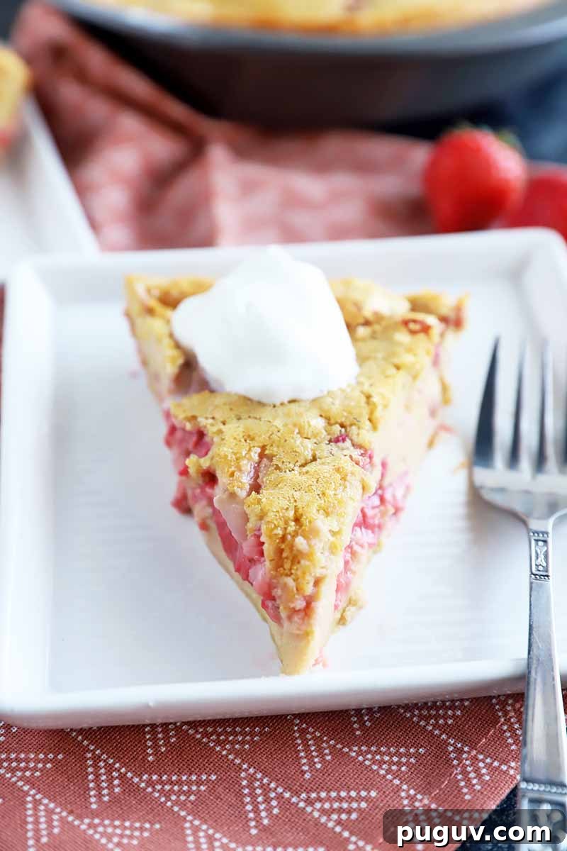 Red Fruit Custard Cake: Elegant Summer Dessert with Fresh Berries 4 Vertical image of a slice of baked dessert studded with berries and topped with whipped cream on a white plate with a metal fork.