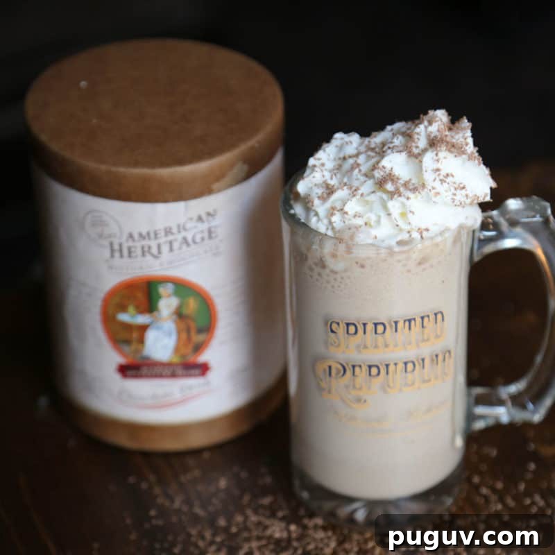 Christmas Cocktail Recipes Everyone Will Love 19 Boozy Hot Chocolate garnished with whipped cream in a glass mug next to American Heritage chocolate