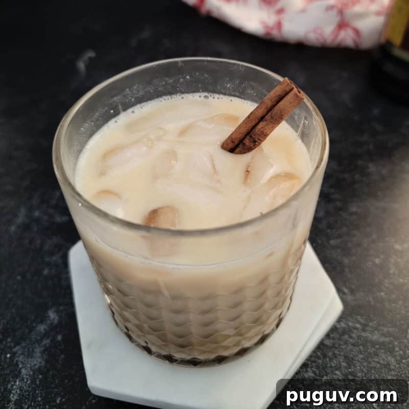 Christmas Cocktail Recipes Everyone Will Love 22 Eggnog White Russian in a crystal glass garnished with a cinnamon stick
