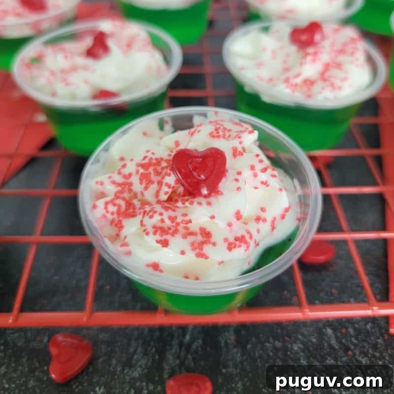 Christmas Cocktail Recipes Everyone Will Love 26 Green grinch jello shot with red heart on a red drying rack