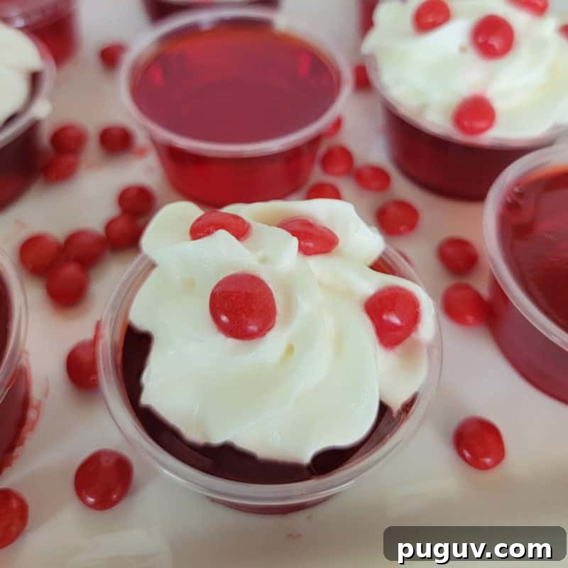 Christmas Cocktail Recipes Everyone Will Love 31 Fireball Jello Shot with whipped cream and a red hot candy on a white plate