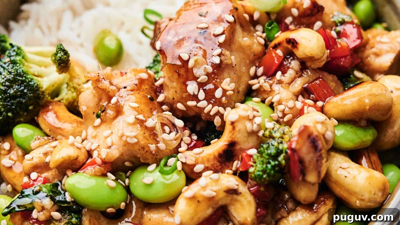 15 Chinese Dishes That Let You Cook Dinner in 30 Minutes 5 Close-up of Cashew Chicken featuring tender chicken, broccoli, edamame, cashews, and red bell peppers. This delightful dish is topped with sesame seeds and served over a bed of rice.