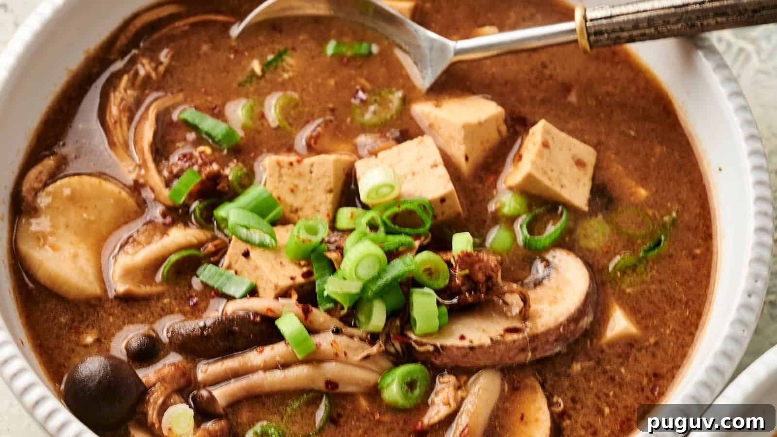 15 Chinese Dishes That Let You Cook Dinner in 30 Minutes 7 Bowl of hot and sour soup with mushrooms, tofu, and sliced green onions, with a spoon on the side.