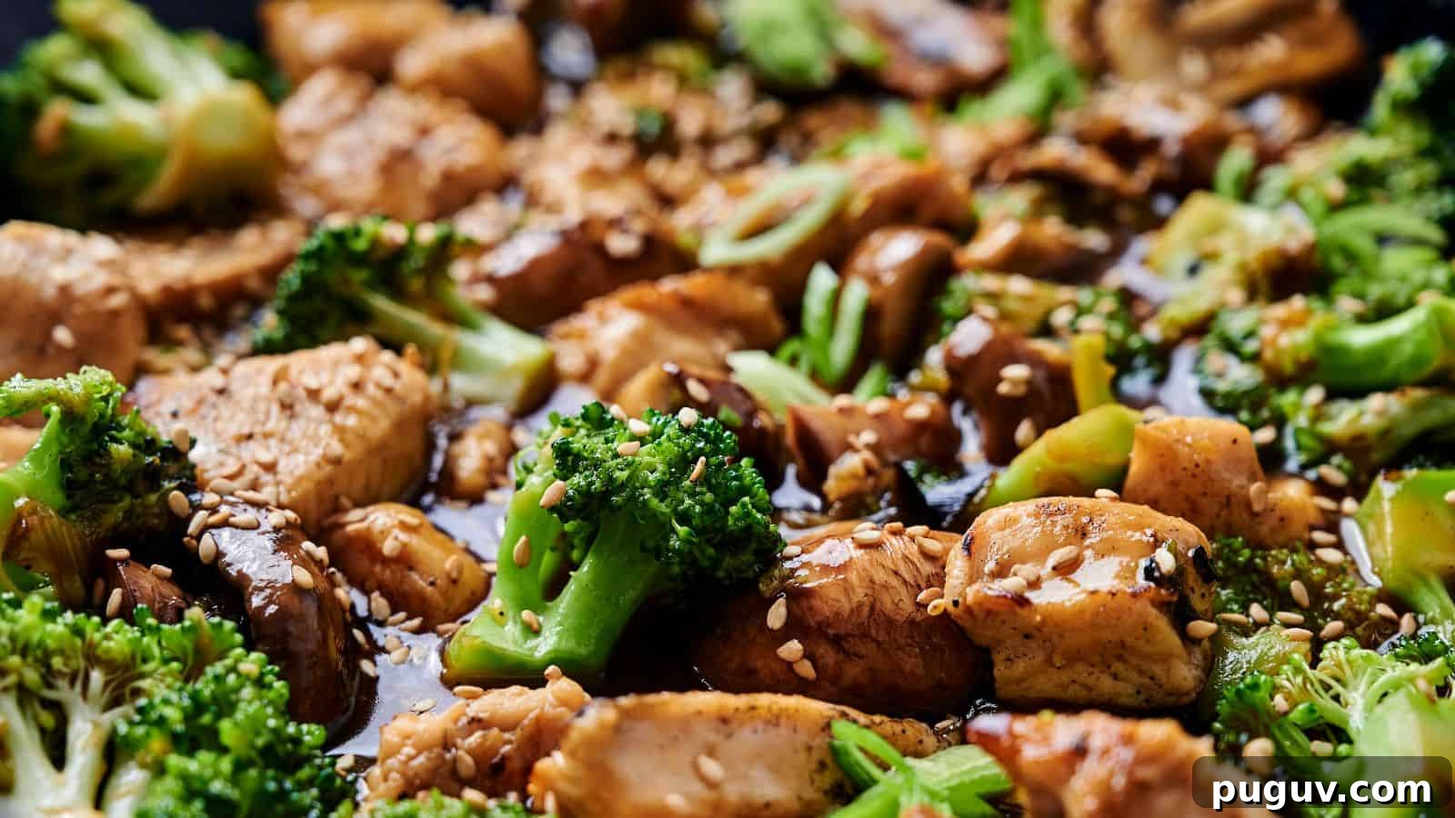 15 Chinese Dishes That Let You Cook Dinner in 30 Minutes 8 Close-up of a stir-fry dish with chicken, broccoli, mushrooms, and sesame seeds, coated in a soy-based sauce.