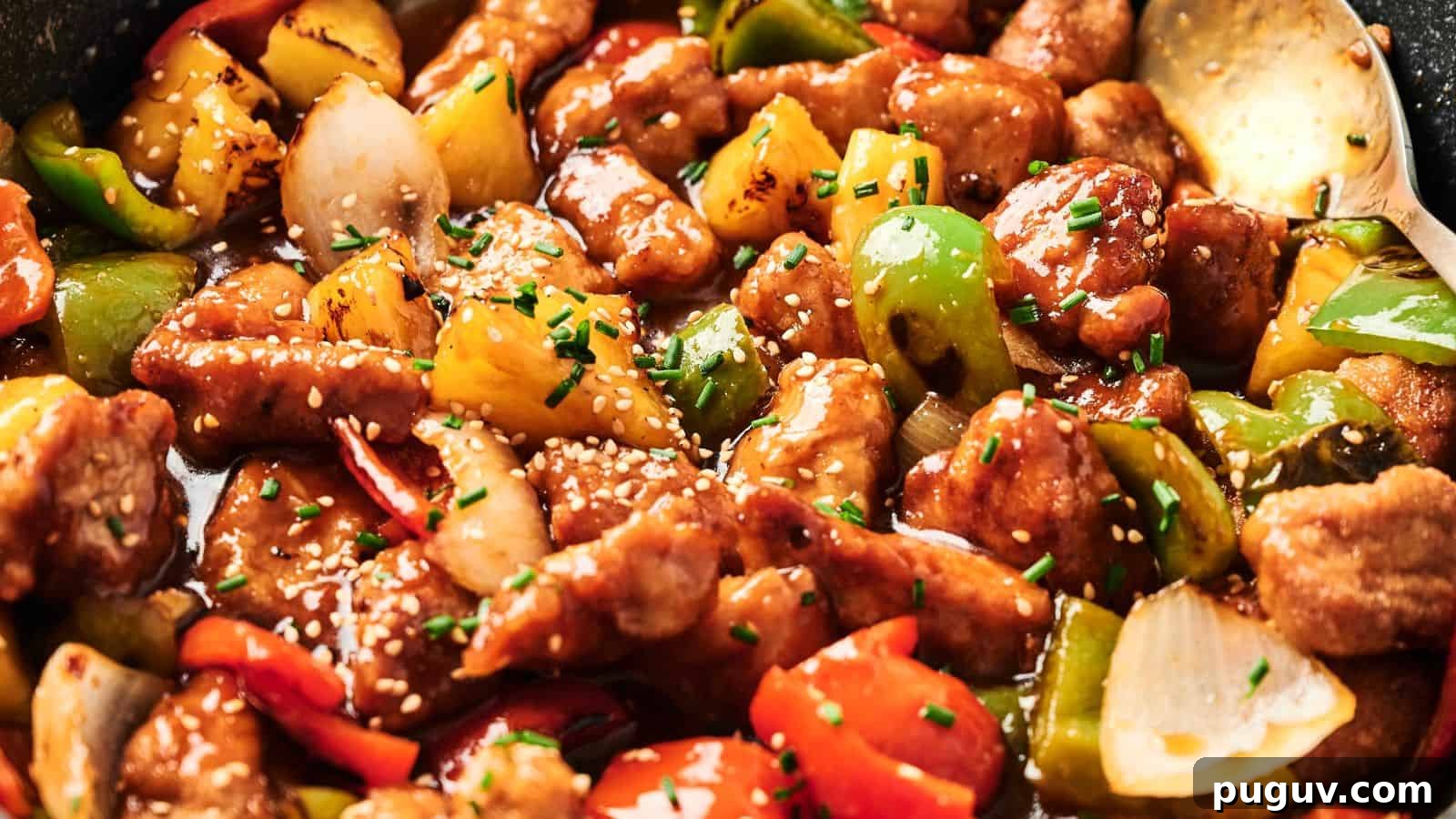 15 Chinese Dishes That Let You Cook Dinner in 30 Minutes 10 Close-up of sweet and sour pork with chunks of bell peppers, onions, and pineapple, garnished with sesame seeds and chives.