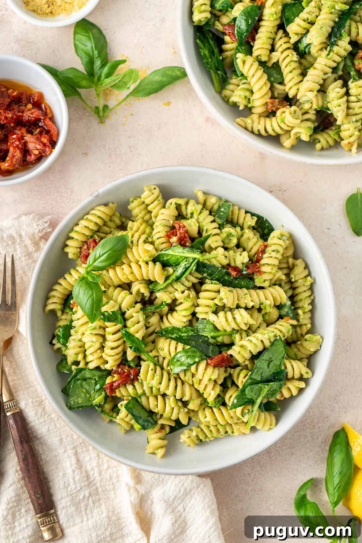 High protein pea pesto pasta served into bowls with spinach and extra basil.