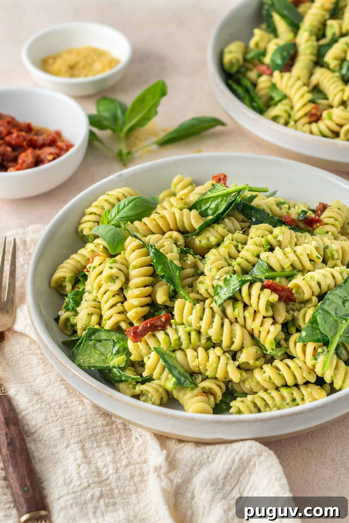 The served pea pesto pasta in bowls garnished with extra basil. 