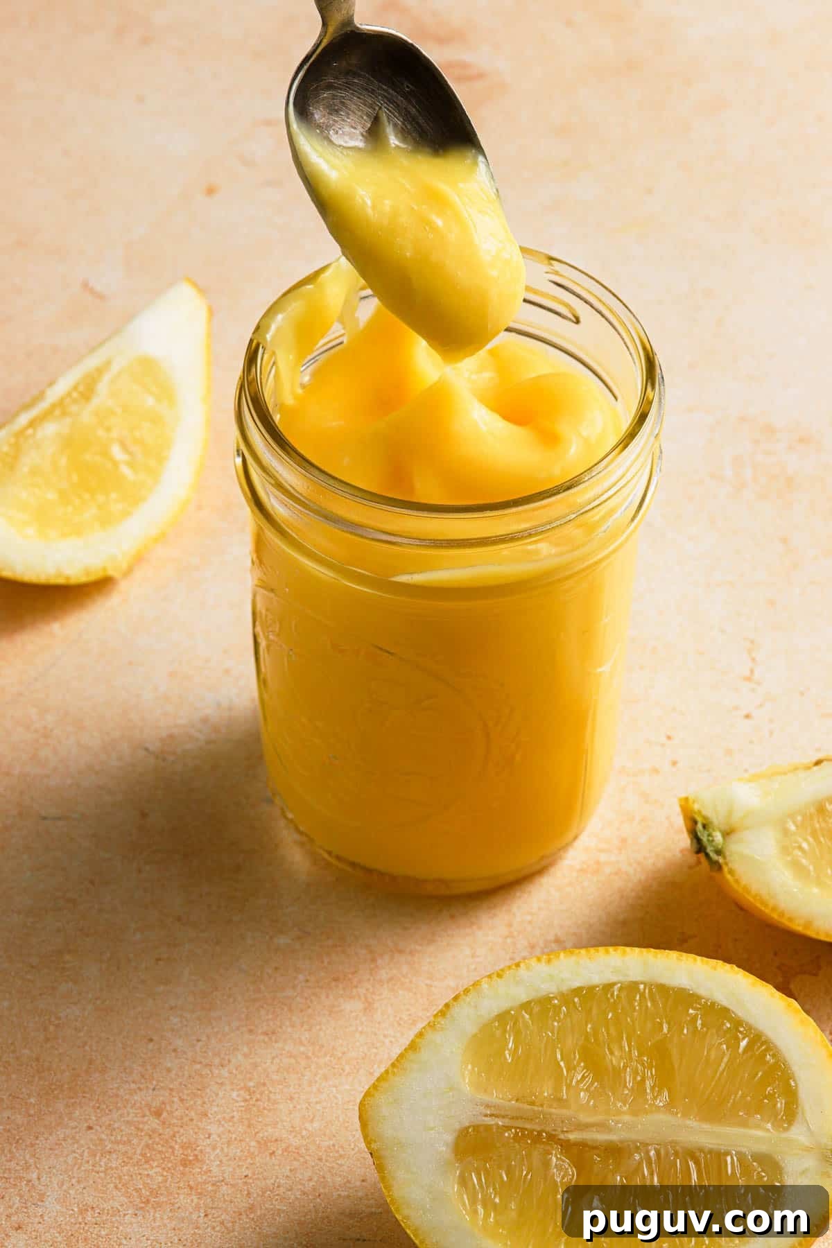 lemon curd in a mason jar with lemons around.