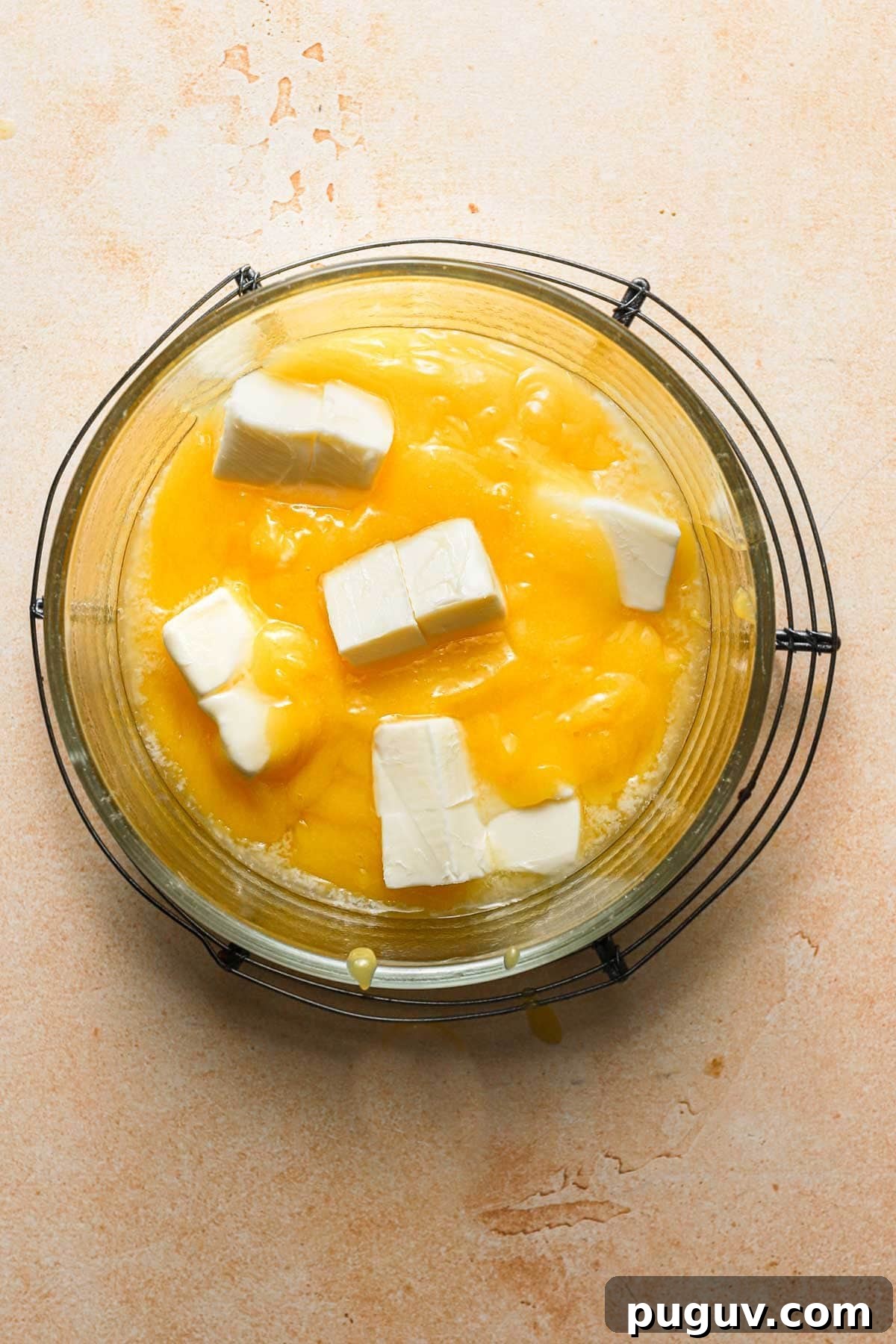 A glass bowl with lemon curd and pieces of butter.
