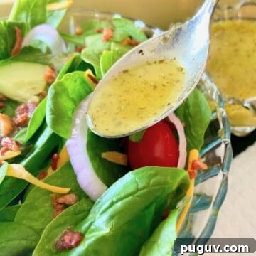 Low sodium salad dressing in spoon drizzling over salad.