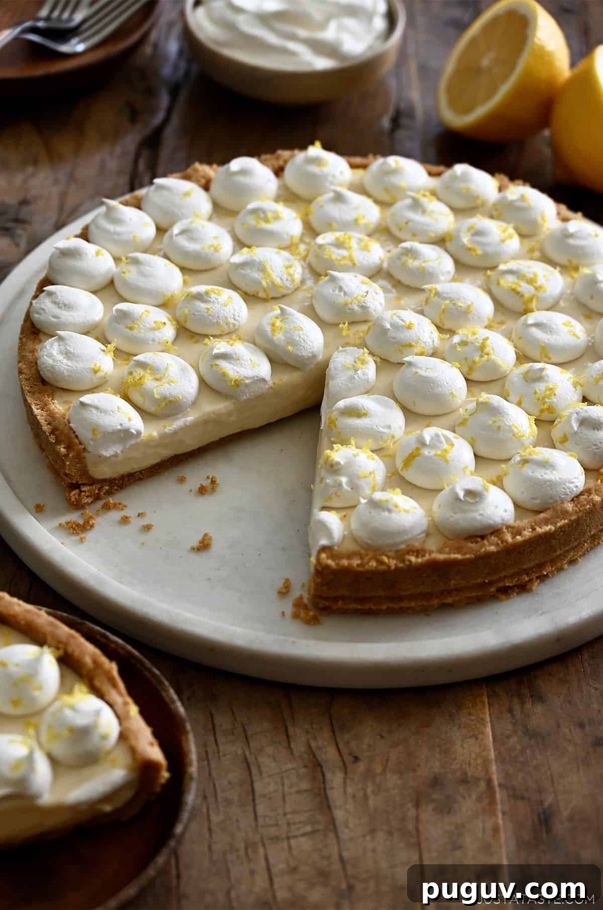 No-Bake Cheesecake Recipe: Creamy No-Bake Cheesecake Slice 5 A no-bake cheesecake with a graham cracker crust topped with dollops of whipped cream and lemon zest with one slice missing.