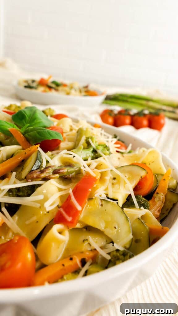 Instant Pot Pasta Primavera Recipe: Quick Veggie One-Pot Meal 3 Side view of primavera pasta salad in white swerving bowl topped with parmesan and fresh basil.