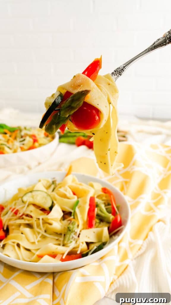 Instant Pot Pasta Primavera Recipe: Quick Veggie One-Pot Meal 5 A fork twirled with pappardelle pasta, a piece of asparagus, and cherry tomato lifted above a bowl of pasta primavera.
