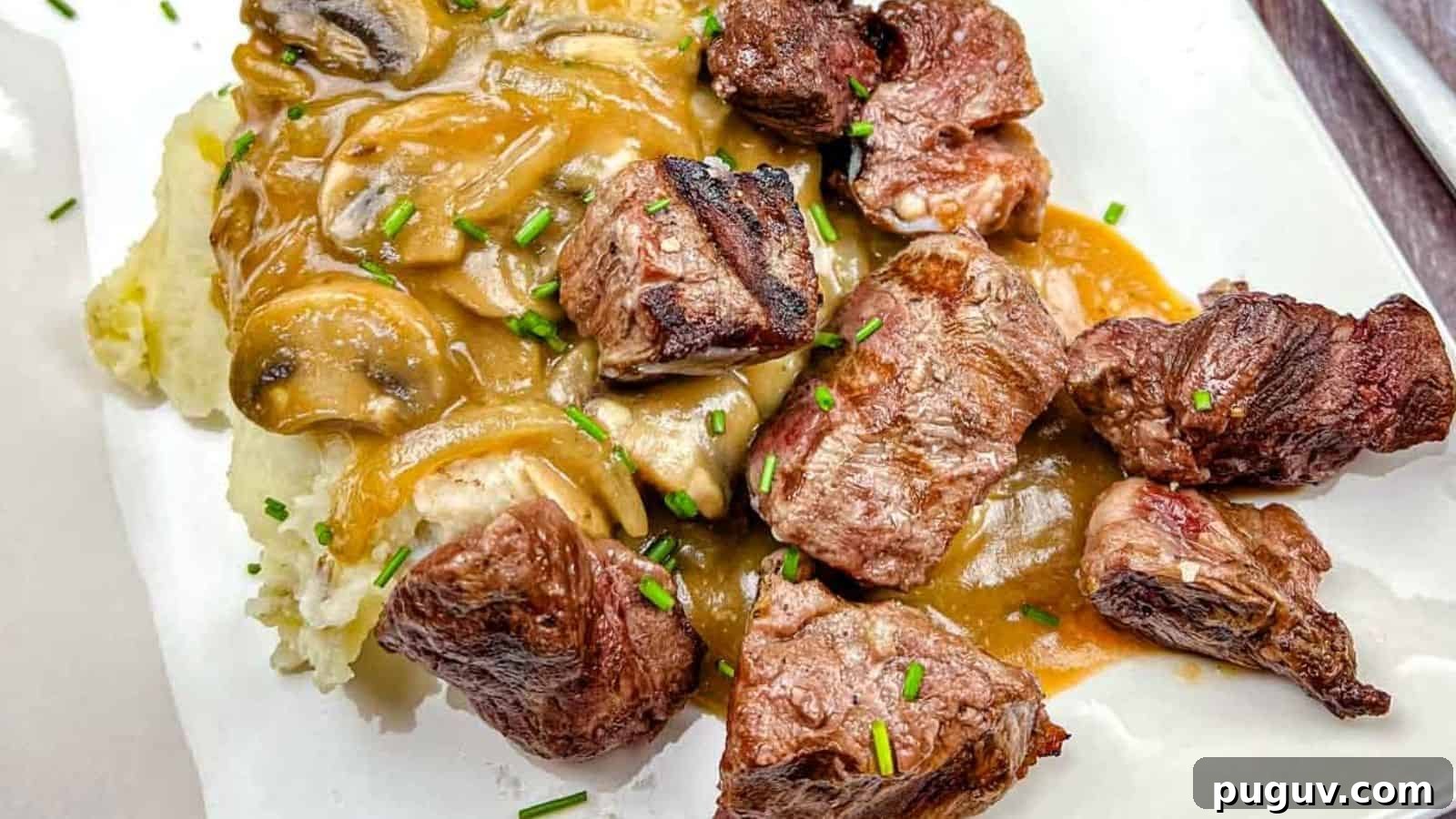 17 Low-Carb Meals That Keep You Full, Energized, and Ready 6 Texas Roadhouse Beef Tips with mushroom gravy over mashed potatoes, garnished with chives on a white plate.