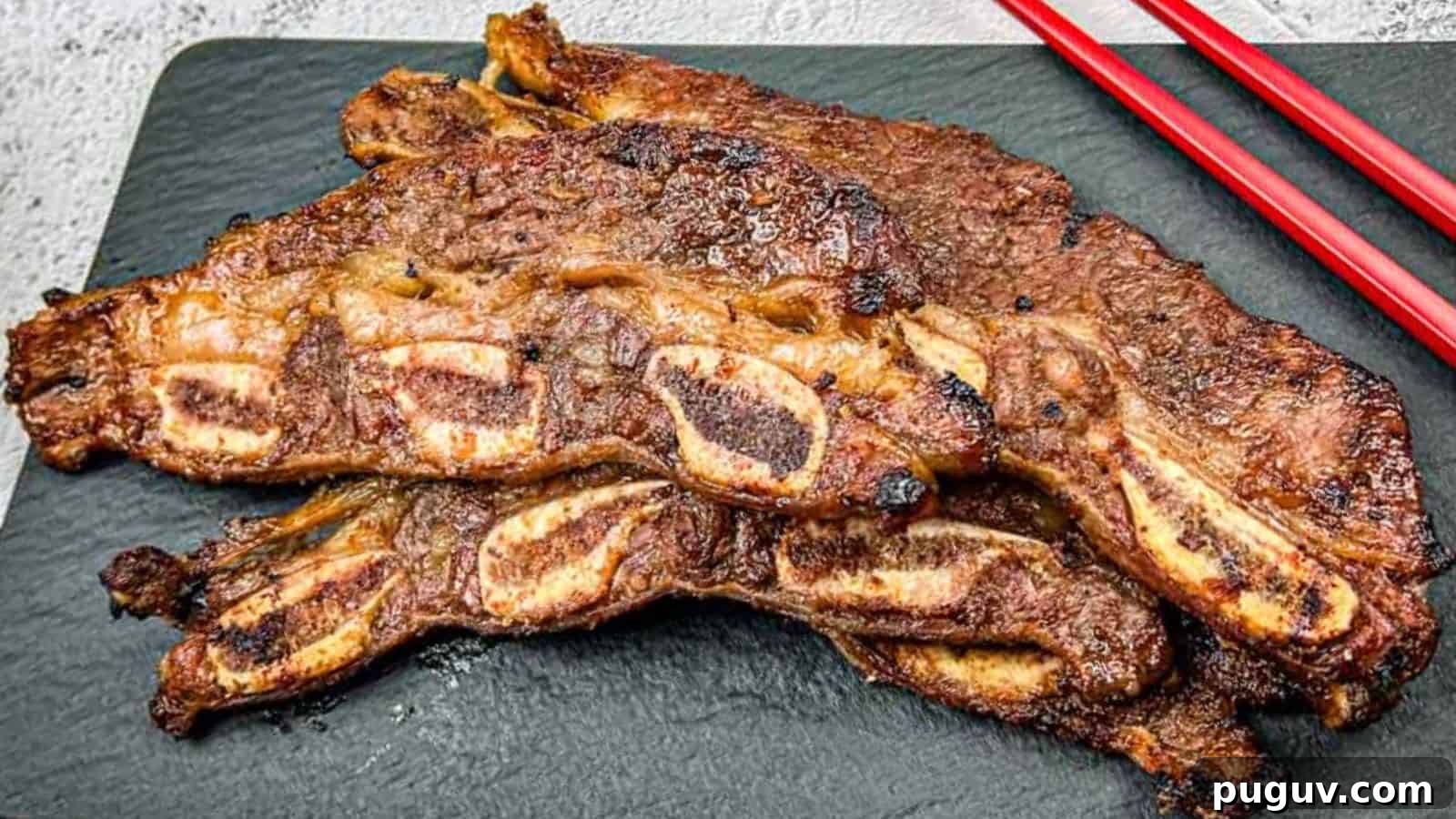 17 Low-Carb Meals That Keep You Full, Energized, and Ready 8 Korean Galbi Ribs on a slate platter with red chopsticks beside them.